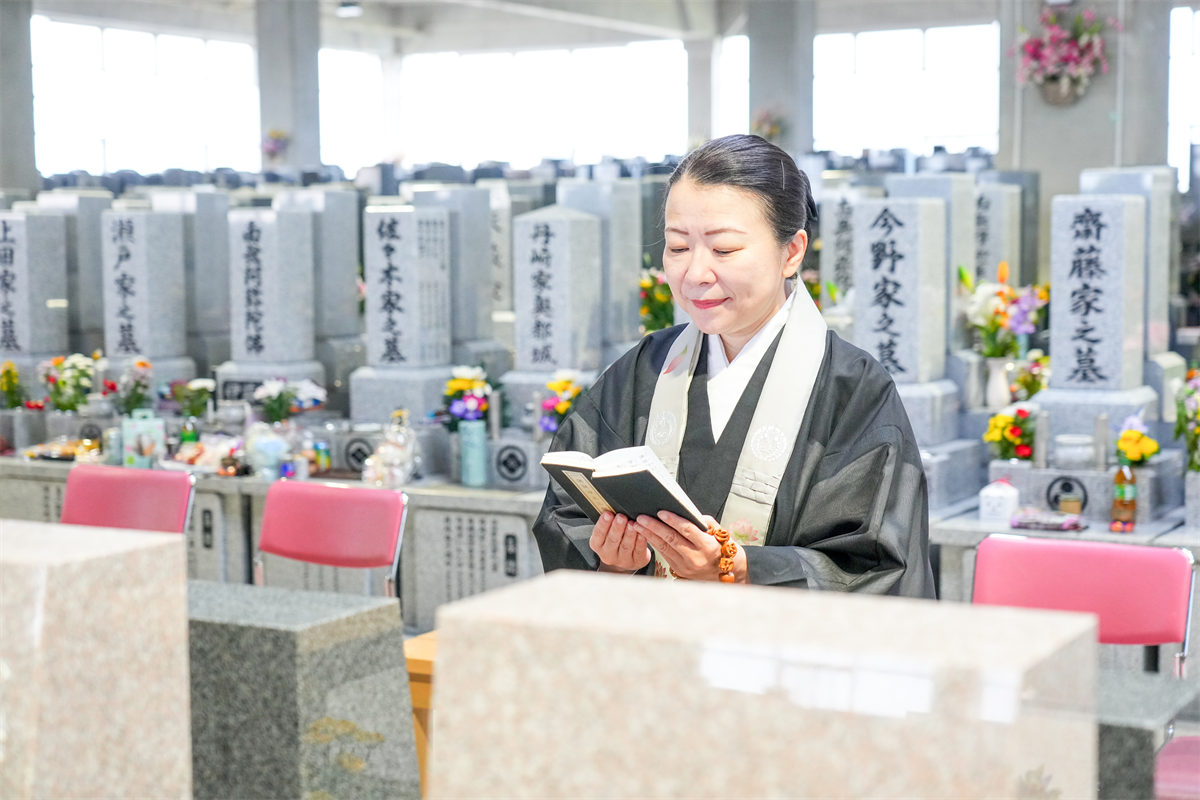 墓前で読経する僧侶